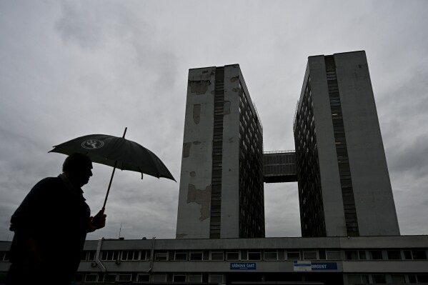 A man walks with an umbrella past the F. D. Roosevelt University Hospital, where Slovak Prime Minister Robert Fico, who was shot and injured on May 15, is being treated, in Banska Bystrica, central Slovakia, Friday, May 17, 2024. Fico, 59, was shot multiple times on Wednesday as he was greeting supporters after a government meeting in the former coal mining town of Handlova. Officials at first reported that doctors were fighting for his life but after a five-hour operation described his situation as serious but stable. (AP Photo/Denes Erdos)