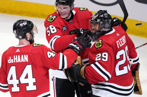 Chicago Blackhawks goaltender Marc-Andre Fleury, right, celebrates with defenseman Calvin de Haan, left, and right wing MacKenzie Entwistle after the Blackhawks defeated the Anaheim Ducks 3-0 in an NHL hockey game in Chicago, Saturday, Jan. 15, 2022. (AP Photo/Nam Y. Huh)