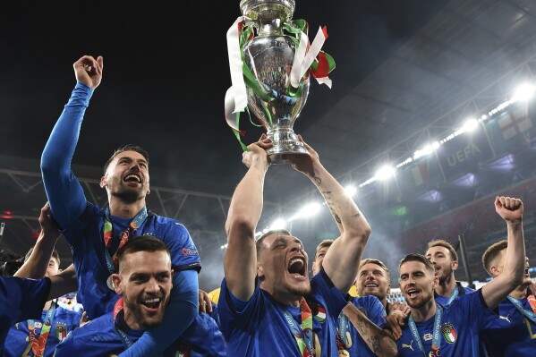 FILE - Italy's Andrea Belotti holds up the trophy after the final of the Euro 2020 soccer final match between England and Italy at Wembley stadium in London, Sunday, July 11, 2021. Just like last time, Italy’s national soccer team is heading into the European Championship following the ignominy of failing to qualify for the World Cup. (Andy Rain/Pool Photo via AP, File)