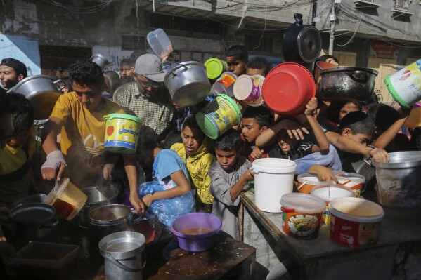 FILE - Palestinians crowd together as they wait for food distribution in Rafah, southern Gaza Strip, Nov. 8, 2023. Catastrophic hunger is so dire in two world hotspots that famine is imminent in northern Gaza and approaching in Haiti, with hundreds of thousands of people in both places struggling to avoid starvation, according to international food security experts and aid groups. (AP Photo/Hatem Ali, File)