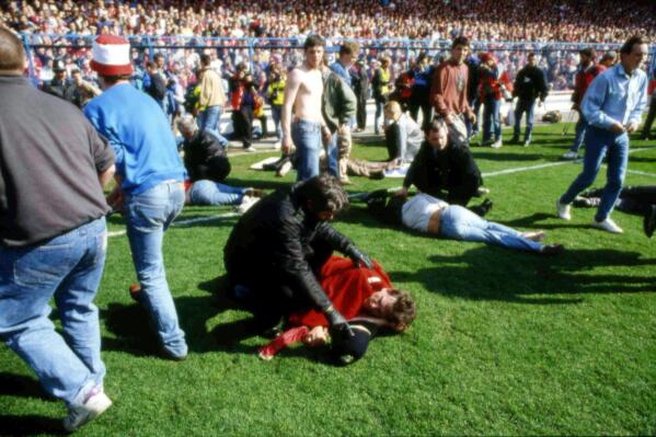 FILE - Stewards and supporters tend and care for wounded supporters on the field at Hillsborough Stadium, in Sheffield, England, April 15, 1989. The crowd deaths from a Halloween festival in Seoul, South Korea, on Saturday, Oct. 29, 2022 have added to the long list of people who have been crushed at a major event. Such tragedies have been occurring around the world for a long time at concerts, sports events and religious gatherings.  (AP Photo, File)