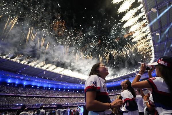 Athletes from the United States watch as fireworks explode during the 2024 Summer Olympics closing ceremony at the Stade de France, Monday, Aug. 12, 2024, in Saint-Denis, France. (AP Photo/Ashley Landis)