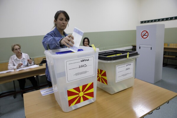 A woman casts her ballots for the parliamentary election and the presidential runoff, at a polling station in Skopje, North Macedonia, on Wednesday, May 8, 2024. Voters in North Macedonia go to the polls Wednesday for a double election — parliamentary and presidential — following a campaign in which the country's aspirations to join the European Union have played a central role. (AP Photo/Boris Grdanoski)