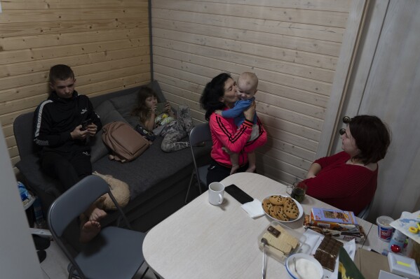 50-year-old Natalia Zhyvohliad, an internally displaced person from Nova Petrivka in the Zaporizhzhia region of Ukraine, is pictured with her children, daughter-in-law and grandson in their temporary modular house in Kolomyya, Ivano-Frankivsk region on Feb. 13, 2024. (AP Photo/Vasilisa Stepanenko)