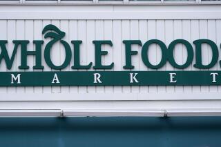 FILE - The Whole Foods Market logo is shown on the front of a store, Wednesday, July 14, 2021, in Cambridge, Mass. Amazon-owned Whole Foods is cutting several hundred jobs as part of a process to simplify its operations. According to a memo sent to employees Thursday, April 20, 2023, by the company's executive team, the grocer planning to reduce its operations from nine regions to six. (AP Photo/Charles Krupa, File)