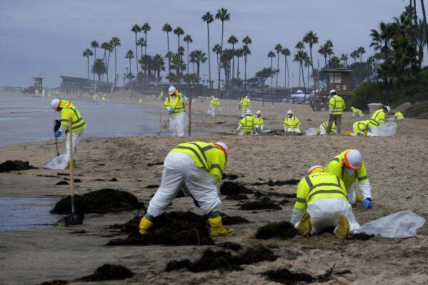 FILE - Workers in protective suits clean the contaminated beach in Corona Del Mar after an oil spill in Newport Beach, Calif., Oct. 7, 2021. The Pipeline and Hazardous Materials Safety Administration is proposing a nearly $3.4 million fine for Amplify Energy Corp over the oil pipeline spill that fouled Southern California beaches.(AP Photo/Ringo H.W. Chiu, File)