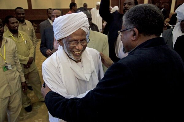 
              FILE - In this Jan. 27, 2014 file photo, Sudanese religious and Islamist political leader Dr. Hassan al-Turabi, center, is greeted as he attends a speech by Sudanese President Omar al-Bashir in Khartoum, Sudan. The Sudanese protesters who succeeded in driving President Omar al-Bashir from power last month say their revolution won’t be complete until they have dismantled what many describe as an Islamist-dominated “deep state” that underpinned his 30-year rule. (AP Photo/Abd Raouf, File)
            