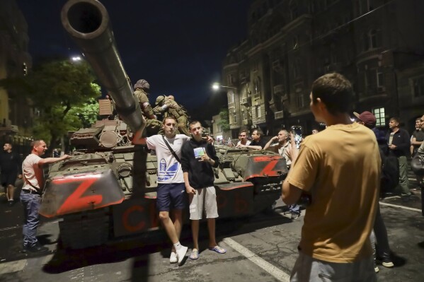 FILE – Mercenaries from the Wagner Group, a private military contractor, sit on a tank in Rostov-on-Don, Russia, on June 24, 2023, as residents pose for a photo near the headquarters of the Southern Military District. (AP Photo, File)