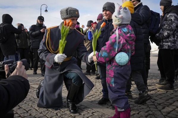 A honour guard soldier gives a flower to a girl on International Women's Day in St. Petersburg, Russia, Friday, March 8, 2024. International Women's Day on March 8 is an official holiday in Russia. Per tradition, men give flowers and gifts to female relatives, friends and colleagues, even though in the past two years flowers have gotten more expensive. Marches, demonstrations and conferences are being held the world over, from Asia to Latin America and elsewhere. (AP Photo/Dmitri Lovetsky)