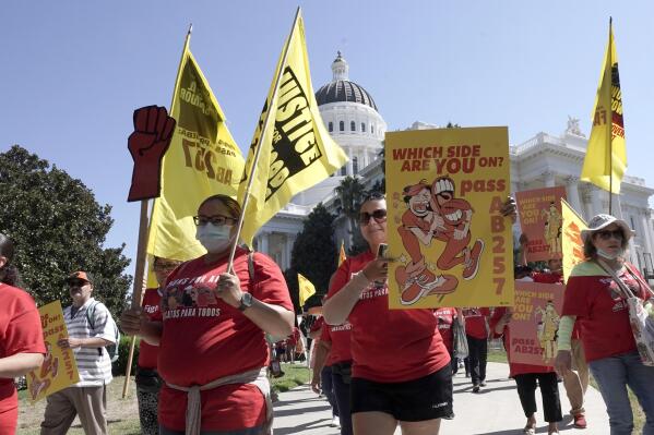 FILE - Fast food workers and their supporters march past the California state Capitol in Sacramento calling on the passage of a bill to provide increased power to fast food workers, Tuesday, Aug. 16, 2022. California Gov. Gavin Newsom on Monday, Sept. 6, 2022, signed a nation-leading measure giving more than a half-million fast food workers more power and protections, despite the objections of restaurant owners who warned it would drive up consumers’ costs. (AP Photo/Rich Pedroncelli, File)