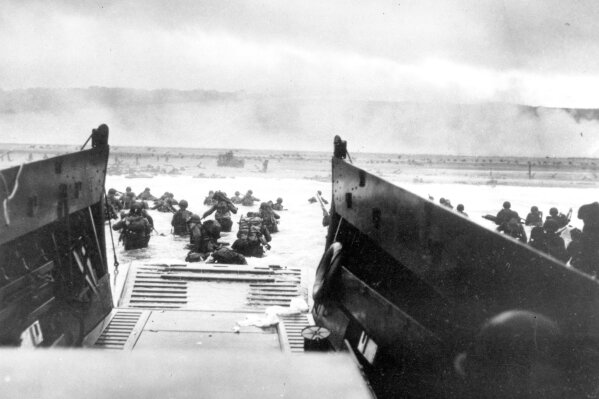 FILE - In this June 8, 1944, file photo, under heavy German machine gun fire, American infantrymen wade ashore off the ramp of a Coast Guard landing craft during the invasion of the French coast of Normandy in World War II. June 6, 2019, marks the 75th anniversary of D-Day, the assault that began the liberation of France and Europe from German occupation, leading to the end World War II. (U.S. Coast Guard via AP, File)
