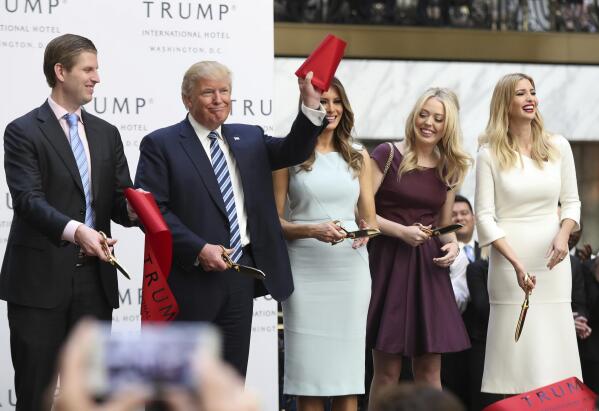 FILE - In this Oct. 26, 2016 file photo, then-Republican presidential candidate Donald Trump, together with his family, from left, Eric Trump, Melania Trump, Tiffany Trump and Ivanka Trump, waves part of a ribbon after cutting the ribbon during the grand opening of Trump International Hotel in Washington. Trump's $200 million hotel inside the federally owned Old Post Office building has become the place to see, be seen, drink, network, even live, for the still-emerging Trump set. It's a rich environment for lobbyists and anyone hoping to rub elbows with Trump-related politicos, despite the veil of ethics questions that hangs overhead.  (AP Photo/Manuel Balce Ceneta, File)