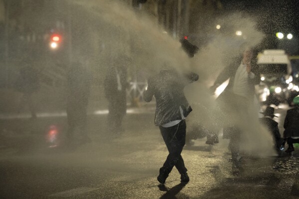 Israeli police use skunk water cannon to disperse ultra-Orthodox Jewish men blocking a street during a protest against a potential new draft law which could end their exemptions from military service in Jerusalem, Monday, March 18, 2024. (AP Photo/Leo Correa)