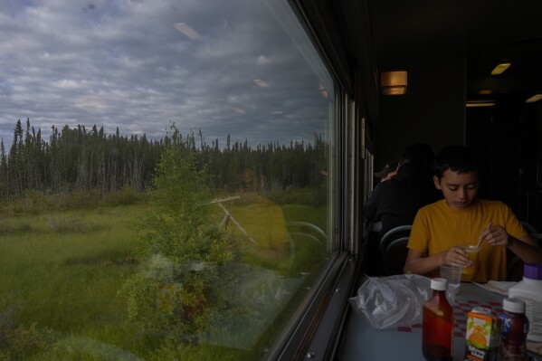 A passenger eats breakfast as a train travels Friday, Aug. 9, 2024, near Ilford, Manitoba. (AP Photo/Joshua A. Bickel)