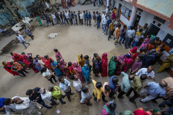 FILE-People stand in queue to cast their votes during the second phase of Gujarat state legislature elections in Ahmedabad, India, Monday, Dec. 5, 2022. From April 19 to June 1, nearly 970 million Indians - or over 10% of the world’s population - will vote in the country's general elections. The mammoth electoral exercise is the biggest anywhere in the world - and will take 44 days to complete before results are announced on June 4. (AP Photo/Ajit Solanki, File)