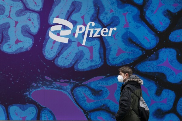 FILE - A man walks by Pfizer headquarters, Friday, Feb. 5, 2021 in New York. Pfizer released a financial outlook for next year that that doesn't match with Wall Street expectations as sales of COVID-19 products slide. Shares tumbled more than 7% before the opening bell Wednesday, Dec. 13, 2023. (AP Photo/Mark Lennihan, File)