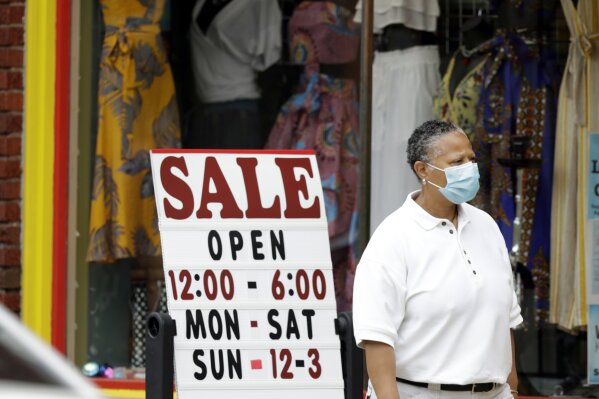 A woman walks past a boutique with a sale sign, Thursday, June 4, 2020, in Cleveland Heights, Ohio. The state says more than 34,000 Ohioans filed unemployment claims during the last week of May. That is the lowest figure since Ohio's stay-at-home orders depressed the economy and led to widespread layoffs. (AP Photo/Tony Dejak)
