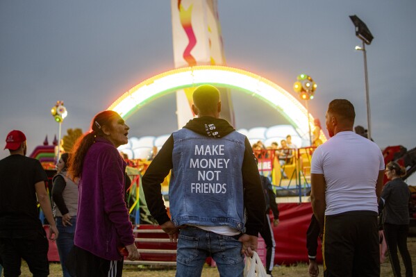 People watch a ride at a fair in Hagioaica, Romania, Saturday, Sept. 16, 2023. For many families in poorer areas of the country, Romania's autumn fairs, like the Titu Fair, are one of the very few still affordable entertainment events of the year. (AP Photo/Alexandru Dobre)