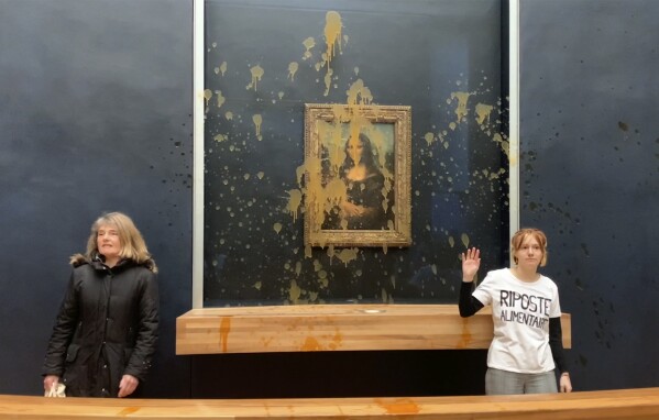 In this grab taken from video, activists react after throwing soup at the glass protecting the Mona Lisa, at the Louvre Museum, Paris, Sunday. Jan. 28, 2024, shouting slogans advocating for a sustainable food system. It comes as French farmers have been protesting for days across the country against several issues, including low wages. (AP Photo/Clement Lanot)