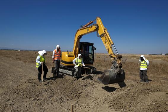 FILE - A bulldozer and workers of Cyprus Missing Persons of the two communities work together during an excavation in a field for missing persons in the Turkish breakaway northern part of divided capital Nicosia, Cyprus, May 31, 2017. U.S. academics who help locate Holocaust mass graves and execution sites in Eastern Europe have used high-tech, ground-penetrating radar to identify potential burial sites of people who disappeared amid war in Cyprus nearly a half century ago. (AP Photo/Petros Karadjias, File)