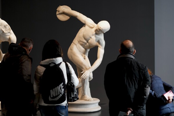 Visitors admire the Discobolus Palombara, a 2nd Century Roman copy of a long-lost Greek bronze original, on display at Rome's National Roman Museum, Sunday, Dec. 3, 2023. Italy's culture minister Gennaro Sangiuliano is reportedly refusing a request by the German State Antiquities Collection in Munich to return the ancient Roman statue that embodied Hitler's Aryan aesthetic, calling it a national treasure. (AP Photo/Andrew Medichini)