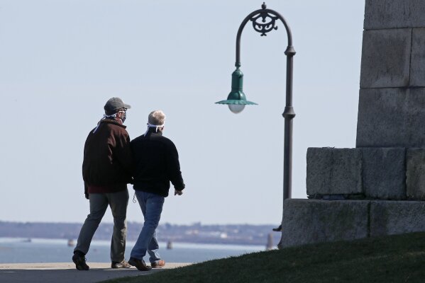 Two men wear masks to protect themselves against COVID-19 as they walk around Castle Island, Monday, April 6, 2020, in Boston. (AP Photo/Elise Amendola)