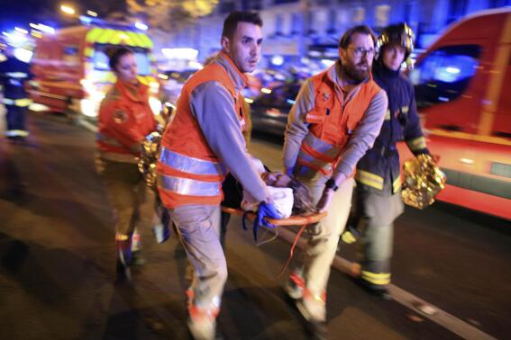 FILE - In this Nov. 13, 2015, file photo, a woman is evacuated from the Bataclan concert hall after a shooting in Paris. The last surviving suspect from the 2015 Paris attacks has told a court he felt "ashamed" after failing to detonate his suicide vest on the bloody night of Nov. 13. (AP Photo/Thibault Camus, File)