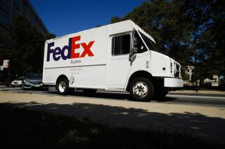 FILE - In this June 26, 2019, file photo, a FedEx truck drives in Philadelphia. FedEx posted surprisingly strong revenue in its latest fiscal quarter, but the delivery giant suspended its financial forecasts for the rest of 2020 because of the uncertain impact of the new coronavirus. (AP Photo/Matt Rourke, File)