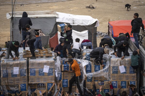 Palestinians loot a humanitarian aid truck as it crossed into the Gaza Strip in Rafah, Sunday, Dec. 17, 2023. (AP Photo/Fatima Shbair)