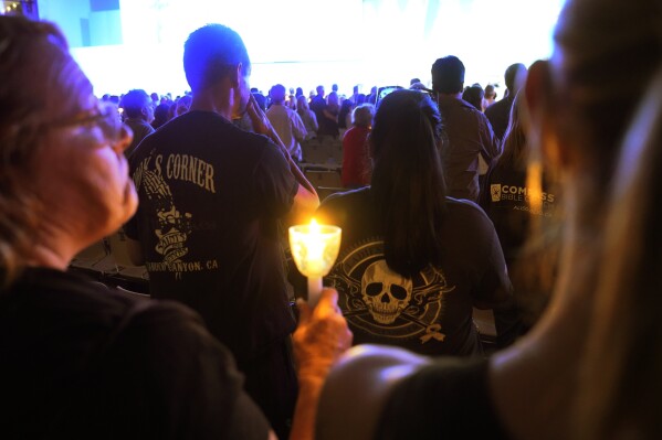 People hold candles during a prayer vigil Friday, Aug. 25, 2023, at Saddleback Church in Lake Forest, Calif., for victims of Wednesday's shootings at Cook's Corner in Trabuco Canyon. (AP Photo/Damian Dovarganes)