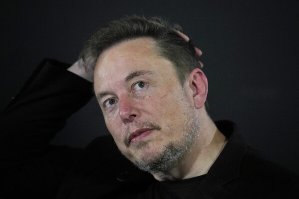 FILE - Elon Musk reacts during an in-conversation event with Britain's Prime Minister Rishi Sunak in London, on Nov. 2, 2023. Elon Musk has restored the X account of conspiracy theorist Alex Jones following a poll posted on the social media platform formerly known as Twitter on Saturday Dec. 9, 2023 that came out in favor of the Infowars host who repeatedly called the 2012 Sandy Hook school shooting a hoax. (AP Photo/Kirsty Wigglesworth, Pool, File)