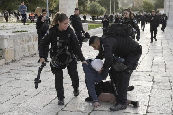 Israeli police arrest a Palestinian woman at the Al-Aqsa Mosque compound following a raid at the site in the Old City of Jerusalem during the Muslim holy month of Ramadan, Wednesday, April 5, 2023. Palestinian media reported police attacked Palestinian worshippers, raising fears of wider tension as Islamic and Jewish holidays overlap.(AP Photo/Mahmoud Illean)