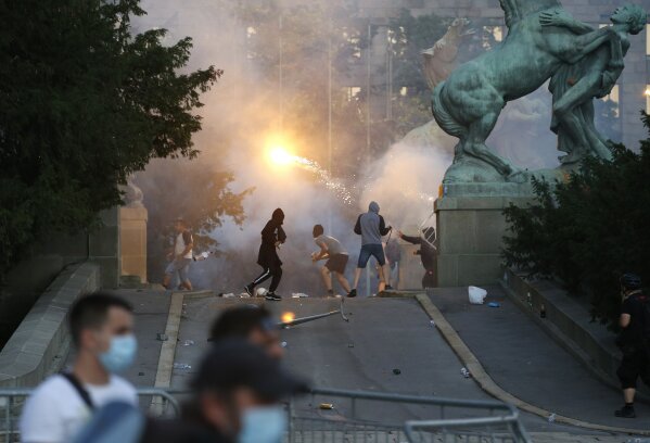 Protesters clash with Serbian riot police in Belgrade, Serbia, Wednesday, July 8, 2020. Police have fired tear gas at protesters in Serbia's capital during the second day of demonstrations against the president's handling of the country's coronavirus outbreak. President Aleksandar Vucic backtracked on his plans to reinstate a coronavirus lockdown in Belgrade this week, but it didn't stop people from firing flares and throwing stones while trying to storm the downtown parliament building. (AP Photo/Darko Vojinovic)