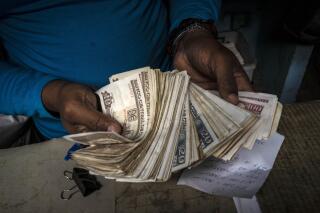 FILE - A worker shows a wad of Cuban pesos in Havana, Cuba, Dec. 11, 2020. The government announced on Aug. 1, 2022 that it will start buying U.S. dollars at an exchange rate five times higher than the official rate, at 110 Cuban pesos per dollar after commission, in an attempt to capture more foreign currency and at the same time combat the informal market. (AP Photo/Ramon Espinosa, File)