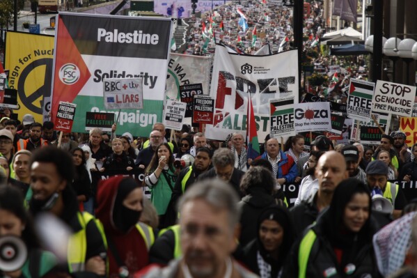 Demonstrators hold up flags and placards during a pro Palestinian demonstration in London, Saturday, Oct. 21, 2023. (AP Photo/David Cliff)