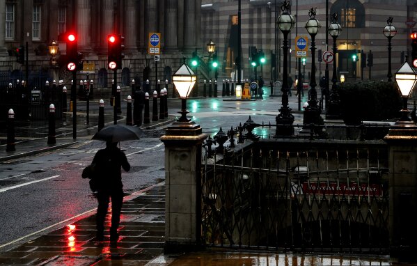 A man with an umbrella walks through a street in the financial area of London, Wednesday, Jan. 13, 2021 during England's third national lockdown to curb the spread of coronavirus. (AP Photo/Alastair Grant)