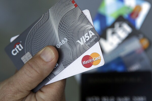 FILE- An unnamed person holds two Visa and Mastercard credit cards in Haverhill, Mass., June 15, 2017. Judge Margo Brodie of the Eastern District of New York said she’s not likely to approve the $30 billion settlement between Visa and Mastercard and merchants who say they’ve overpaid on swipe fees. (AP Photo/Elise Amendola, File)