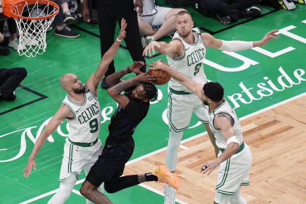 Boston Celtics' Derrick White (9), Kristaps Porzingis (8) and Jayson Tatum (0) block a shot by Dallas Mavericks' Derrick Jones Jr. (55) during the second half of Game 1 of basketball's NBA Finals on Thursday, June 6, 2024, in Boston.(AP Photo/Michael Dwyer)