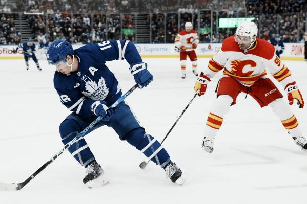 Toronto Maple Leafs' Mitchell Marner, left, takes the puck away from Calgary Flames' Nazem Kadri, right, during second-period NHL hockey game action in Toronto, Saturday, Dec. 10, 2022. (Chris Young/The Canadian Press via AP)