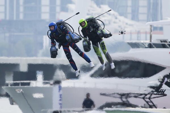 Jet suit pilots race in Dubai, United Arab Emirates, Wednesday, Feb. 28, 2024. Dubai on Wednesday hosted what it called its first-ever jet suit race. Racers zipped along a route with the skyscrapers of Dubai Marina looming behind them, controlling the jet engines on their hands and their backs. (AP Photo/Jon Gambrell)