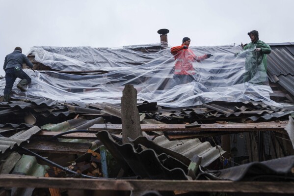 People use plastic to cover a roof of a house damaged by a Russian strike in Korostyshiv, Zhytomyr region, Ukraine, Sunday, May 25, 2025. (AP Photo/Evgeniy Maloletka)