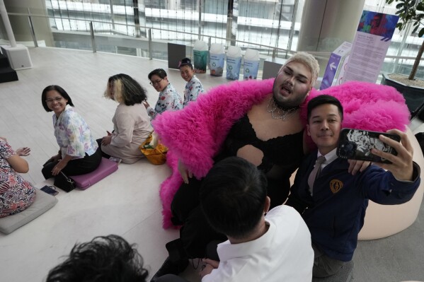 A participant, right, takes a selfie with a drag queen at a news conference on the Bangkok Pride in Bangkok, Thailand, Thursday, May 9, 2024. Thailand is kicking off its celebration for the LGBTQ+ community's Pride Month with a parade on Saturday, as the country is on the course to become the first nation in Southeast Asia to legalize marriage equality. (AP Photo/Sakchai Lalit)