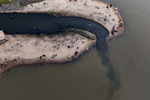People fish next to drainage that flows into the Paraguay River in Asuncion, Paraguay, Sunday, Jan. 28, 2024. (AP Photo/Jorge Saenz)