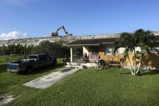 FILE - Rehabilitation work takes place on top of the Herbert Hoover Dike surrounding Lake Okeechobee, just a few feet from a home on Nov. 1, 2019, in Pahokee, Fla. Hurricane tides overtopped the original dike in 1926 and 1928, washed away houses and caused over 2,500 deaths. After 18 years, a $1.5 billion project was officially completed Wednesday, Jan. 25, 2023, to repair the sprawling dike around Florida's Lake Okeechobee that protects thousands of people from potentially catastrophic flooding during hurricanes. (AP Photo/Robert F. Bukaty, File)