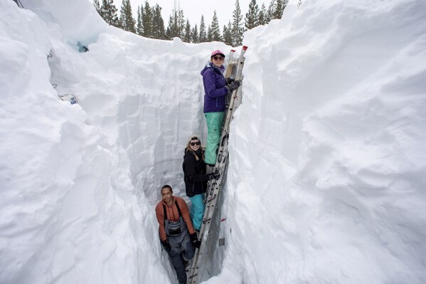 FILE - Working inside a nearly 18-foot-deep snow pit at the UC Berkeley Central Sierra Snow Lab, from left, Shaun Joseph, Claudia Norman, Helena Middleton take measurements of snow temperatures ahead of a weather storm on March 9, 2023, in Soda Springs, Calif. A new study finds the snow deluge in California, which quickly erased a two decade long megadrought, was essentially a once-in-a-lifetime rescue from above. The study authors coined the term “snow deluge” for one-in-20-year heavy snowfalls. (Karl Mondon/Bay Area News Group via AP, File)
