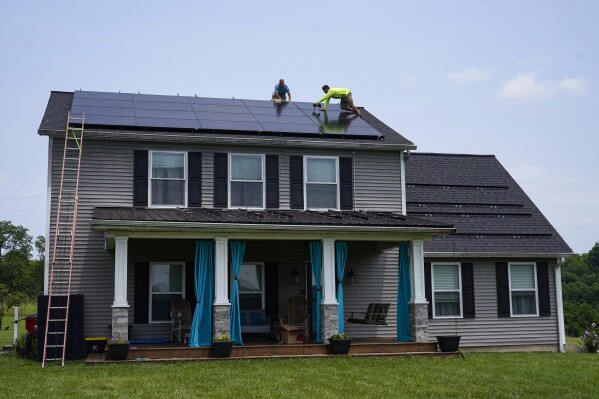 Brian Hoeppner, left, and Nicholas Hartnett, owner of Pure Power Solar, install a solar panel on the roof of a home in Frankfort, Ky., Monday, July 17, 2023. Since passage of the Inflation Reduction Act, it has boosted the U.S. transition to renewable energy, accelerated green domestic manufacturing, and made it more affordable for consumers to make climate-friendly purchases, such as installing solar panels on their roofs. (AP Photo/Michael Conroy)