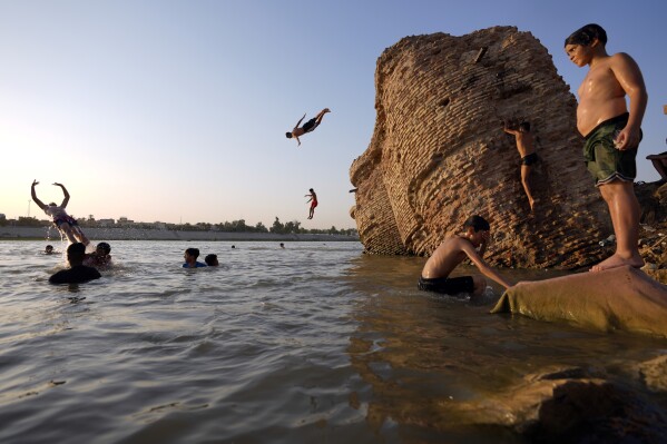 Iraqi men and their sons swim in the Tigris river to beat the heat in Baghdad, Iraq, Thursday, July 13, 2023. (AP Photo/Hadi Mizban)