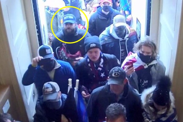 In this image from U.S. Capitol Police security video, released and annotated by the Justice Department in the Statement of Facts supporting an arrest warrant, Taylor Taranto, circled in yellow, enters the U.S. Capitol through the Upper West Terrace door on Jan. 6, 2021, in Washington. A Capitol riot suspect who had guns and hundreds of rounds of ammunition in his van when he was arrested near former President Barack Obama’s Washington home has been indicted on federal firearms charges. Taranto was already facing misdemeanor charges stemming from his alleged involvement in the Jan. 6 riot. (Justice Department via AP)