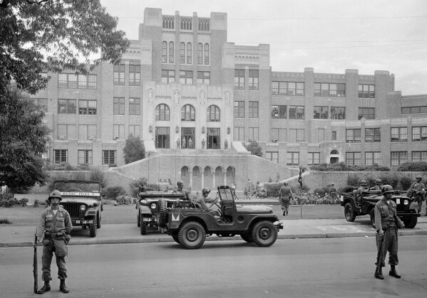 FILE - In this Sept. 26, 1957, file photo, members of the 101st Airborne Division take up positions outside Central High School in Little Rock, Ark. The troops were on duty to enforce integration at the school. During the Civil Rights era, Presidents Johnson, John F. Kennedy and Dwight Eisenhower used the law to protect activists and students desegregating schools. Eisenhower sent the 101st Airborne to Little Rock, Arkansas, to protect Black students integrating Central High School after that state’s governor activated the National Guard to keep the students out. (AP Photo/File)