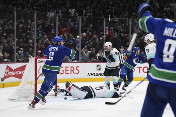 Vancouver Canucks' Brock Boeser (6) celebrates Elias Pettersson's goal against Seattle Kraken goalie Martin Jones (30) during the third period of an NHL hockey game Thursday, Dec. 22, 2022, in Vancouver, British Columbia. (Darryl Dyck/The Canadian Press via AP)